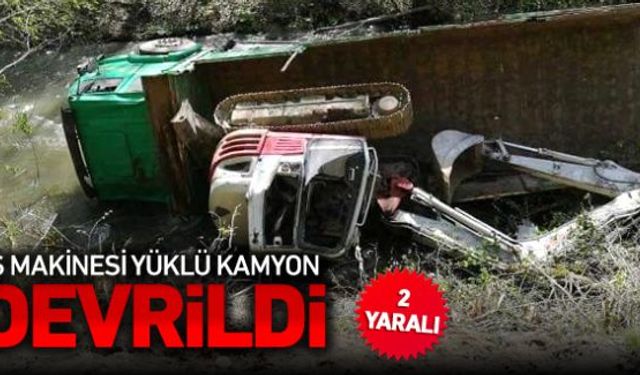 Orman yolunda meydana gelen kazada iş makinesi yüklü kamyon devrilerek 2 kişi yaralandı